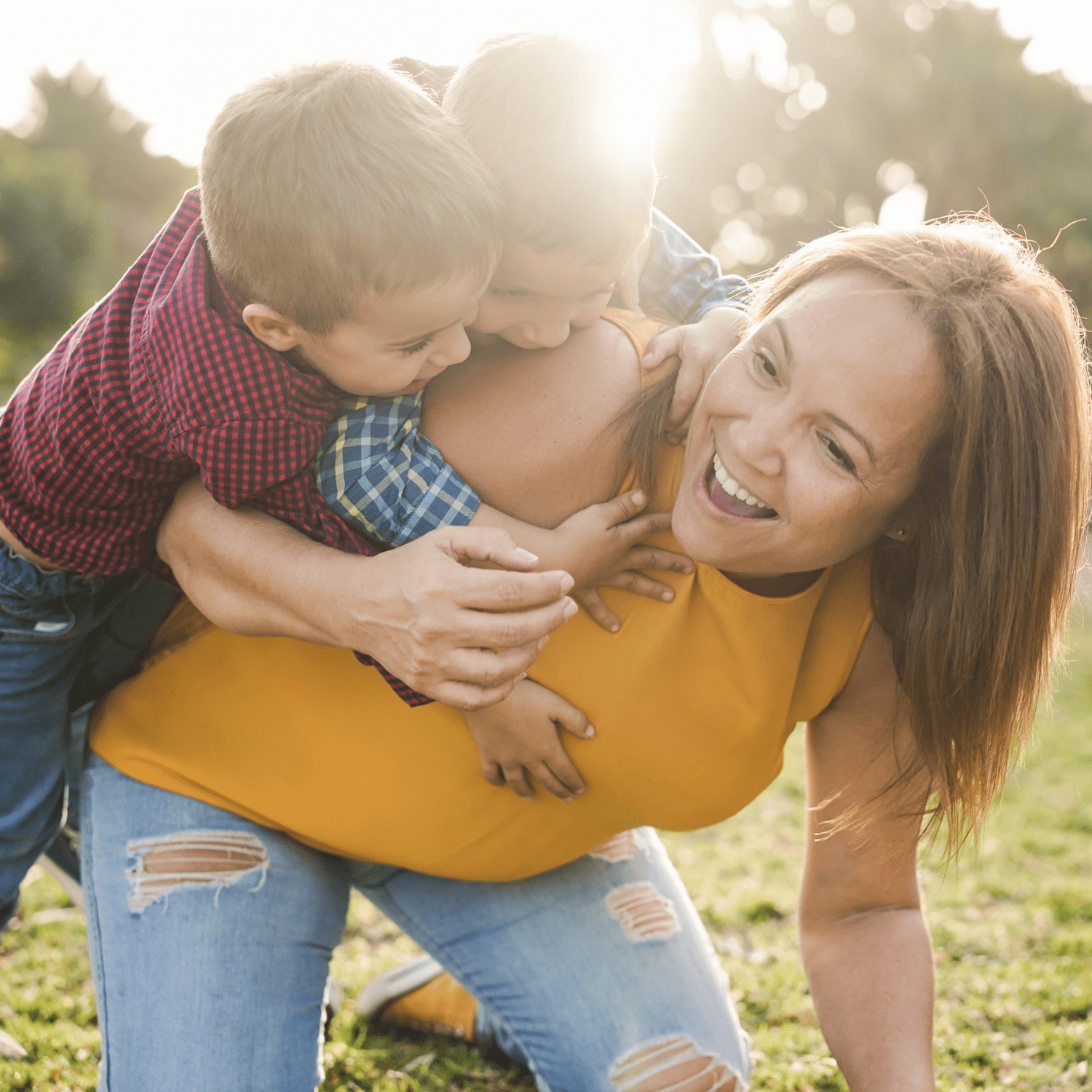 A joyful mother playing with her two young sons outdoors, laughing and enjoying quality family time.